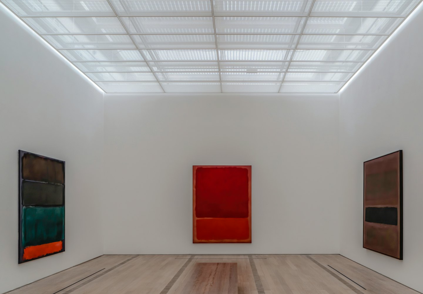 Trzy abstrakcyjne obrazy wiszące na białych ścianach galerii.
