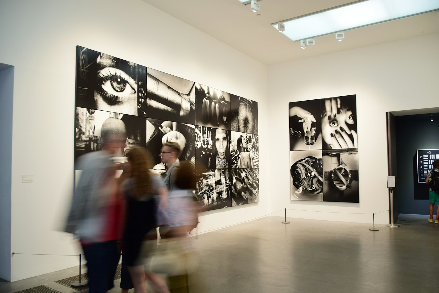 Odwiedzający podziwiają duże czarno-białe fotografie w nowoczesnej galerii sztuki.